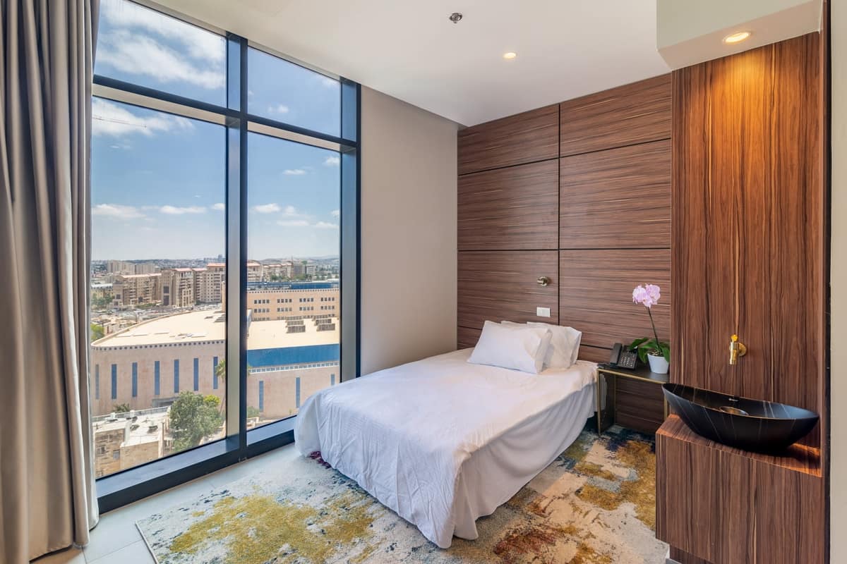 Bright guest room with floor-to-ceiling windows and Jerusalem city view at Hotel Yirmiyahu 33, Romema